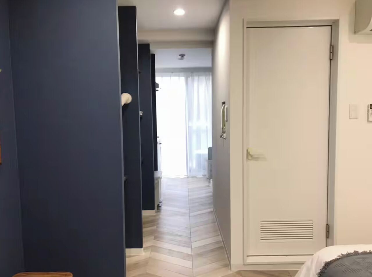 A hotel corridor with a door, a radiator, and a window with curtains.