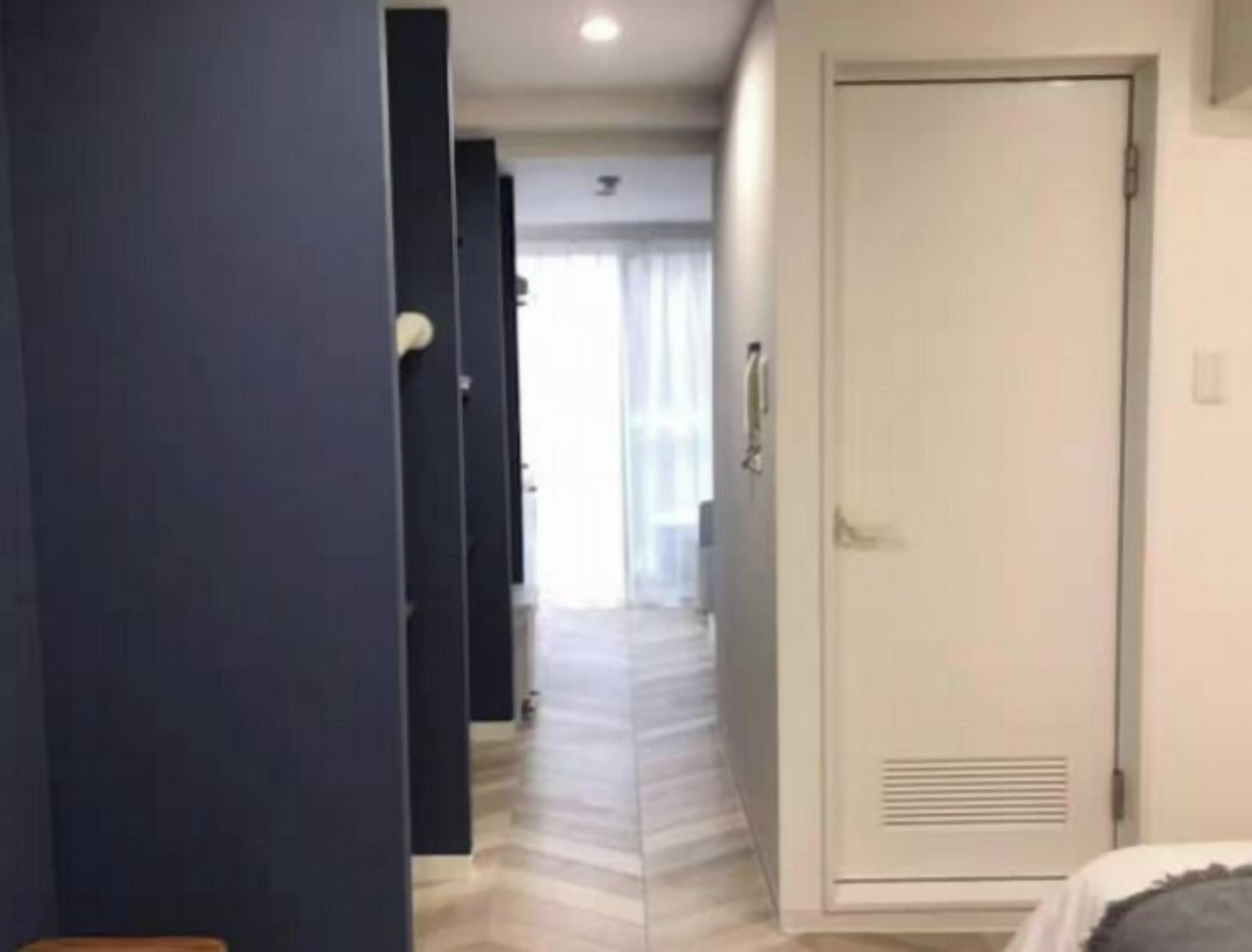 A hotel corridor with a wooden floor, a white door, and a blue wall.