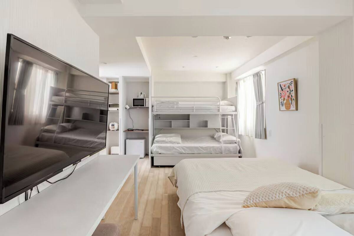 A modern hotel room with a TV, bunk beds, a desk, and a microwave.