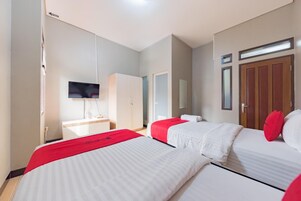 Una habitación de hotel con dos camas, televisión, armario y espejo.