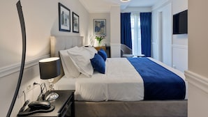 A hotel room with a bed, bedside table, lamp, and a flat-screen TV mounted on the wall. - Classic Hotel by Athens Prime Hotels (Athens)