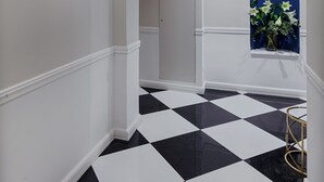 A hallway with black and white checkered flooring, white walls, and a sign indicating room numbers G01-G04. - Classic Hotel by Athens Prime Hotels (Athens)