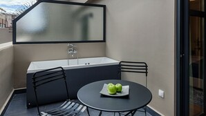 A modern outdoor balcony with a round table, two chairs, a small bar area, and a glass door leading to an interior space. - Classic Hotel by Athens Prime Hotels (Athens)