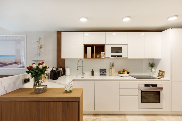 A modern kitchen with white cabinets, a wooden countertop, a built-in oven, and a sink.