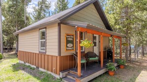 En lille, etetages hytte med veranda, med skiltet "Forest View Lodging 222 Parkway D", omgivet af træer.