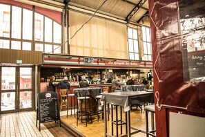 A bar with a red awning, wooden stools, and a chalkboard menu.