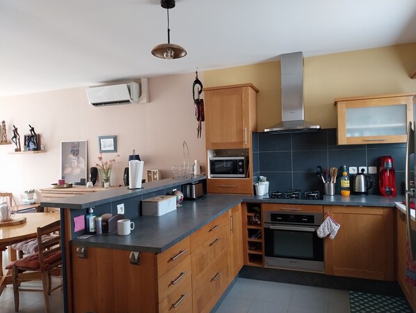A modern kitchen with wooden cabinets, a built-in oven, a microwave, and a coffee maker.