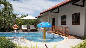 Piscina com fonte de água, espreguiçadeiras e uma palmeira.