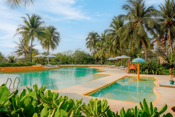 A swimming pool with palm trees and umbrellas. - Pax Ana Doc Let Resort & Spa (Ninh Hoa)