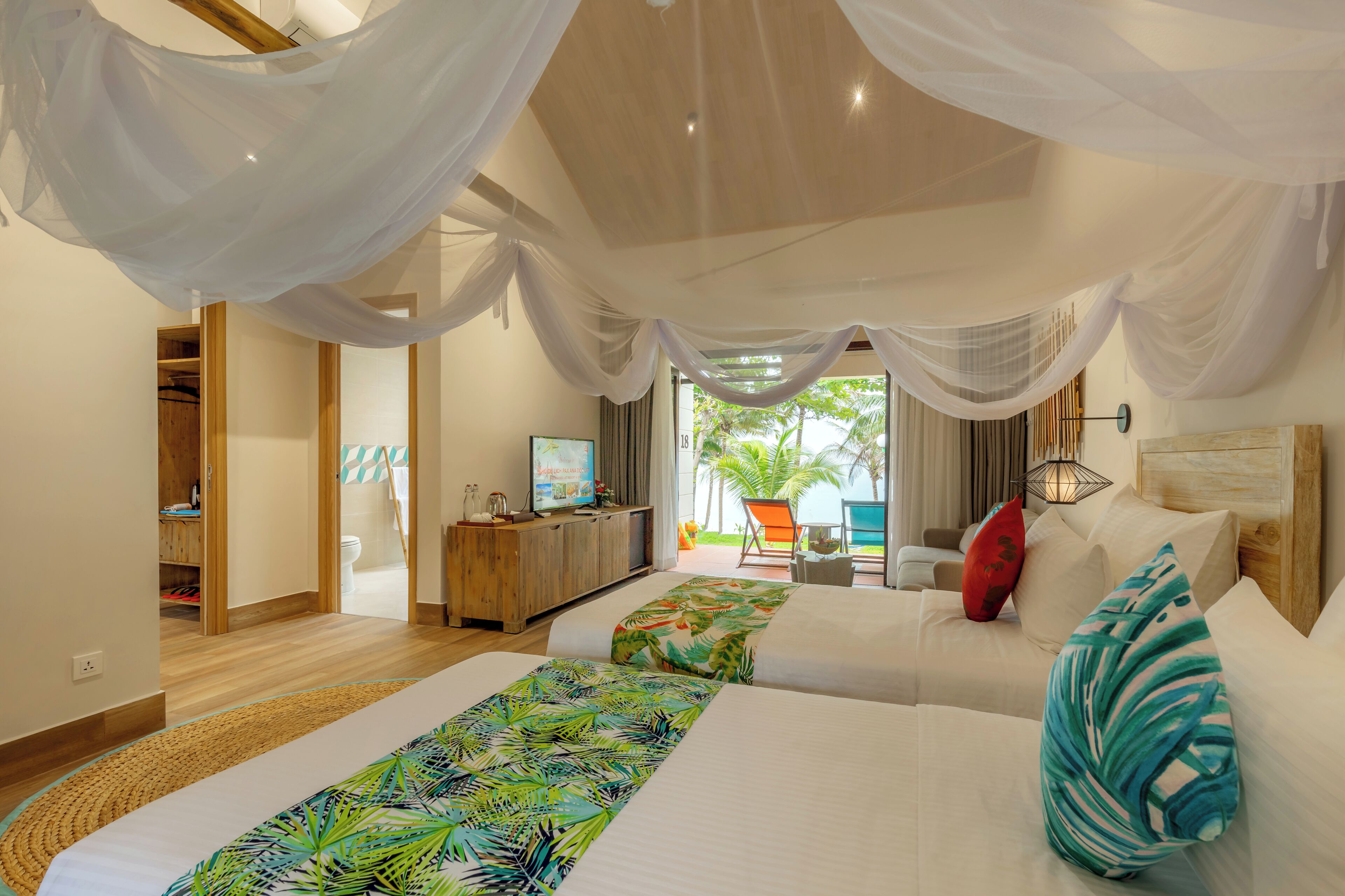A bedroom with a bed, a TV, a wooden cabinet, and a view of the outdoors. - Pax Ana Doc Let Resort & Spa (Dong Ninh Hoa)