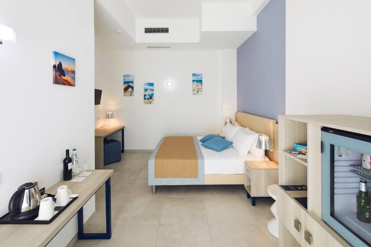 A hotel room with a bed, bedside table, desk, and a minibar.