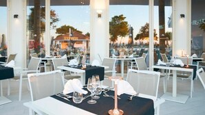An outdoor dining area with tables set for two, featuring white chairs and black tablecloths. - Tui Blue Tropea – Baia di Riaci Resort (Santa Domenica)