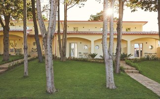 A building with a yellow facade, arched doorways, and a tiled roof.