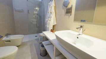 A modern bathroom with a large sink, a bidet, a shower, and a mirror.