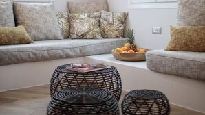 Una sala moderna con un sofá gris, cojines estampados y un bol de frutas sobre una mesa de centro de madera.