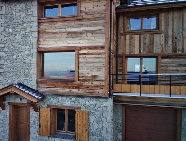 Une cabane en rondins à plusieurs étages, avec des murs en pierre, de nombreuses fenêtres et un balcon.