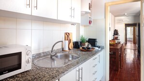 Una cucina moderna con mobili bianchi, un piano di lavoro in granito, un forno a microonde integrato e un lavello in acciaio inossidabile.