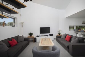 Un salon moderne comprenant deux canapés, une table basse, un téléviseur et un coin repas.