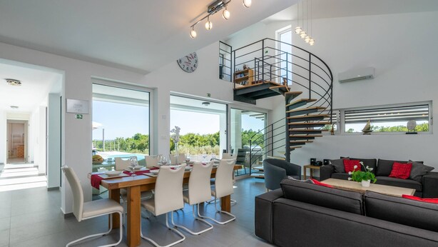 A spacious living area with a modern staircase, a dining table set for four, and a comfortable seating area. - Villa Elsa with 4 bedrooms (Krnica)