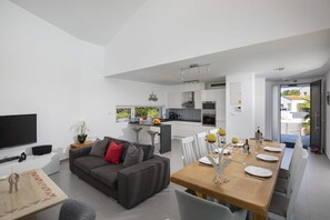 A modern living space with a dining area, kitchen, and a TV.