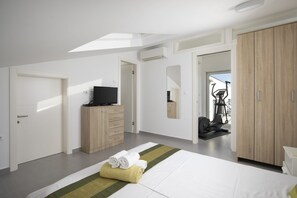 Een moderne hotelkamer met een bed, een televisie, een kledingkast en een fitnessapparaat.