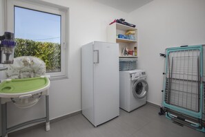 A laundry room with a washing machine, a dryer, and a drying rack.