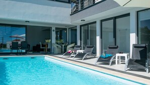 A modern pool area with lounge chairs and a glass-enclosed patio. - Villa Elsa with 4 bedrooms (Krnica)