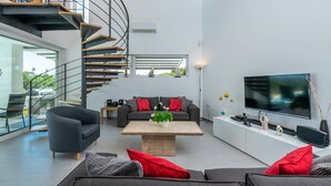 A modern living room with a spiral staircase, a large flat-screen TV, and a minimalist design. - Villa Elsa with 4 bedrooms (Krnica)