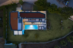A modern house with a swimming pool, a covered patio, and a fenced yard.
