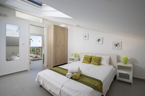A modern bedroom with a skylight, a large bed with pillows, a nightstand, and a view of a balcony.