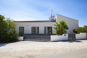 A modern two-story building with a flat roof, large windows, and a gated entrance.