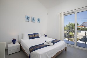 Une chambre à coucher avec un lit, une table de chevet, une lampe et une vue sur l’extérieur.