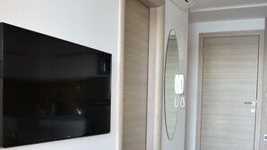 A modern hallway with a flat-screen TV mounted on the wall, a built-in bench, a mirror, and a door. - Villa Vita (Novalja)