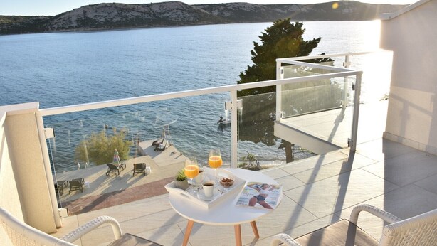 A balcony with a table set for breakfast, overlooking a body of water and hills. - Villa Vita (Novalja)