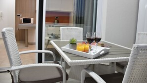 A dining area with wicker chairs, a glass table, and a tray with drinks and fruit. - Villa Vita (Novalja)