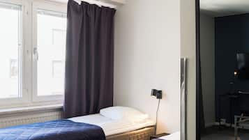 Quarto de hotel com duas camas, um espelho grande, uma escrivaninha e uma janela com cortinas.