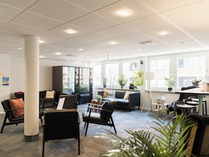 A modern office space with a seating area, a vending machine, and large windows.