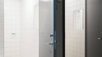 A modern bathroom with white tiles, a shower area, and a toilet.