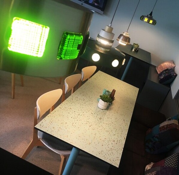 A dining area with a table, chairs, a potted plant, and pendant lights. - Hotel N Hostel Malmö City (Malmö)