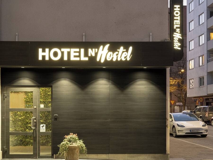 Un edificio con un cartel que dice 'HOTEL N'Hostel' y una planta en maceta al frente.