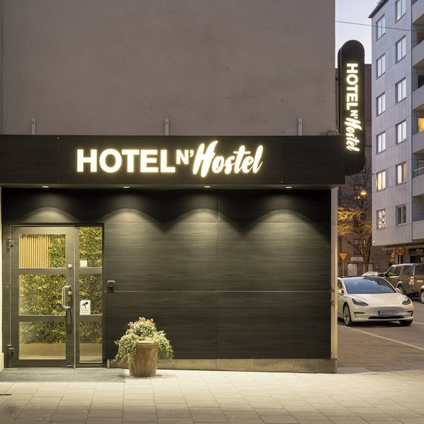 A building with a sign reading 'HOTEL N'Hostel' and a potted plant in front.