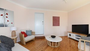 Un salon moderne avec un canapé, une table basse, un téléviseur et des œuvres d’art accrochées aux murs.
