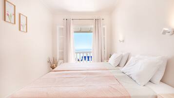 Un dormitorio con dos camas, vistas al mar y un balcón con barandilla.