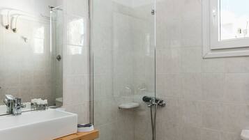 A modern bathroom with a glass shower enclosure, a wooden vanity, and a white sink.