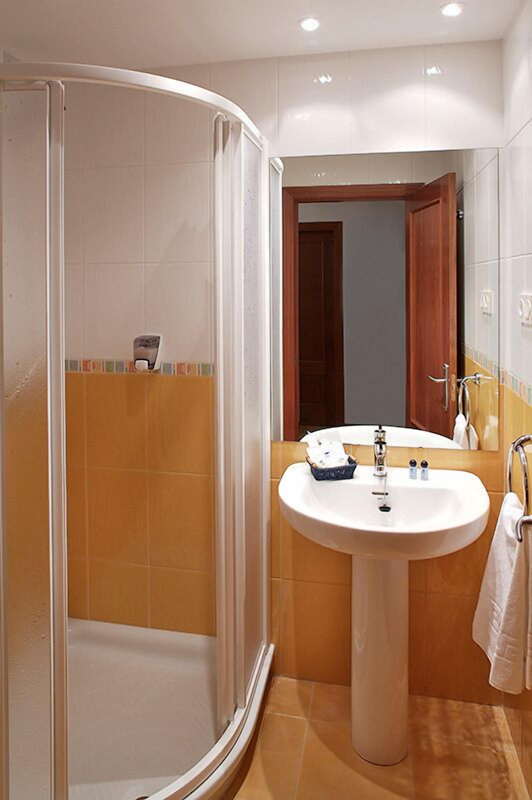 Un baño con cabina de ducha, lavamanos y espejo.
