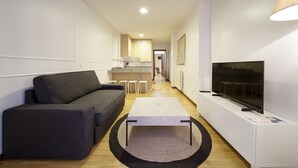 Ein modernes Wohnzimmer mit einer Couch, einem Couchtisch und einem Fernseher auf einem Schrank.