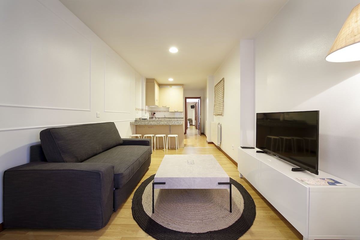 Ein modernes Wohnzimmer mit einer Couch, einem Couchtisch und einem Fernseher auf einem Schrank.