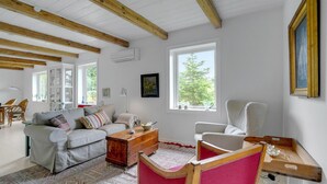Een woonkamer met een bank, fauteuils, een houten dressoir en een rode vloerkleed.