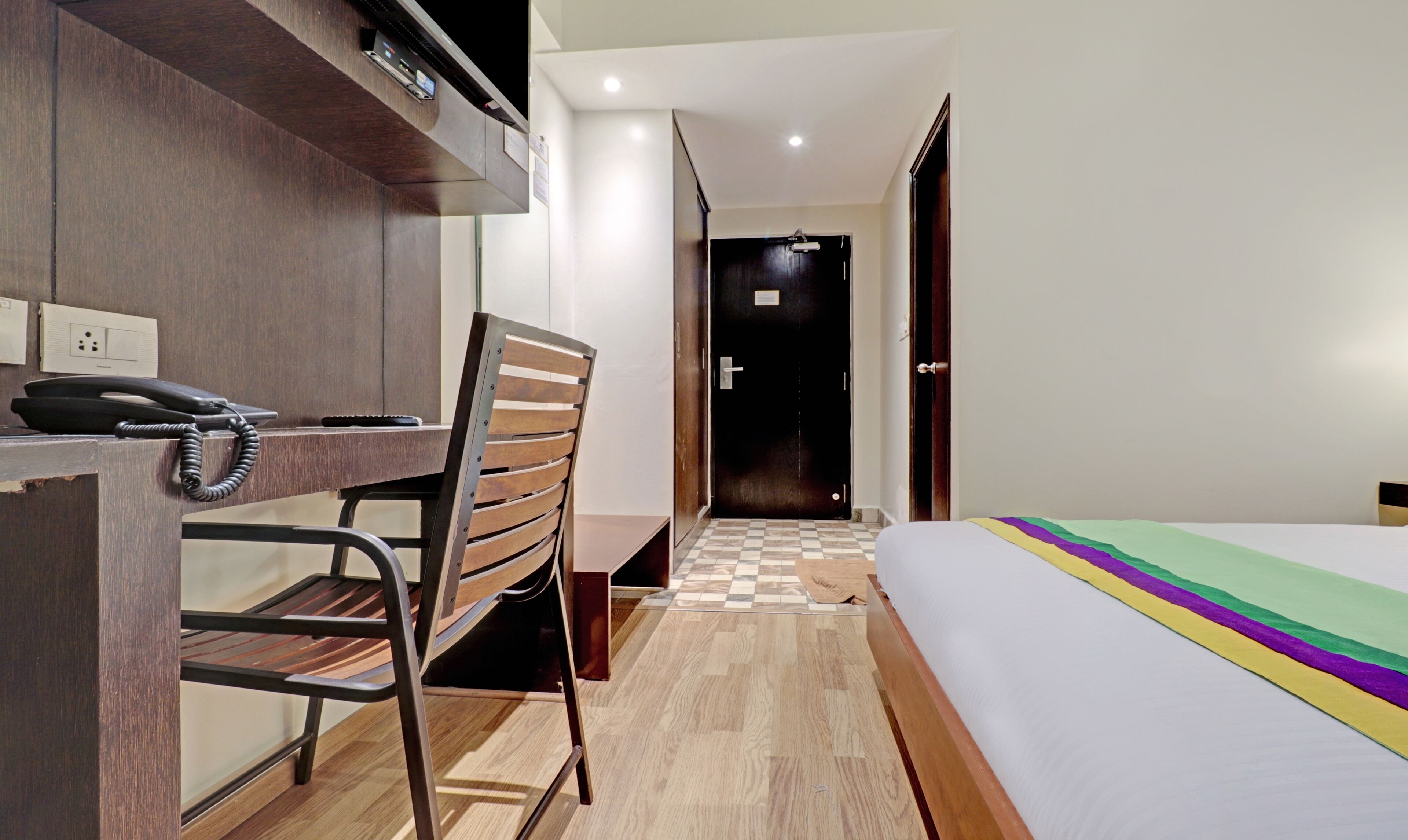 Una habitación de hotel con escritorio, silla, cama y piso a cuadros.