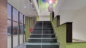 A staircase with a handrail, a green wall, and a window with a view of a building outside. - Treebo Astor HSR Layout (Bengaluru)